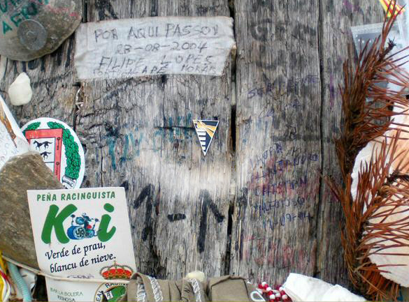 El pin de la Autoridad Portuaria de Ferrol clavado en el poste de madera de la Cruz de Ferro, un mito en el Camino de Santiago